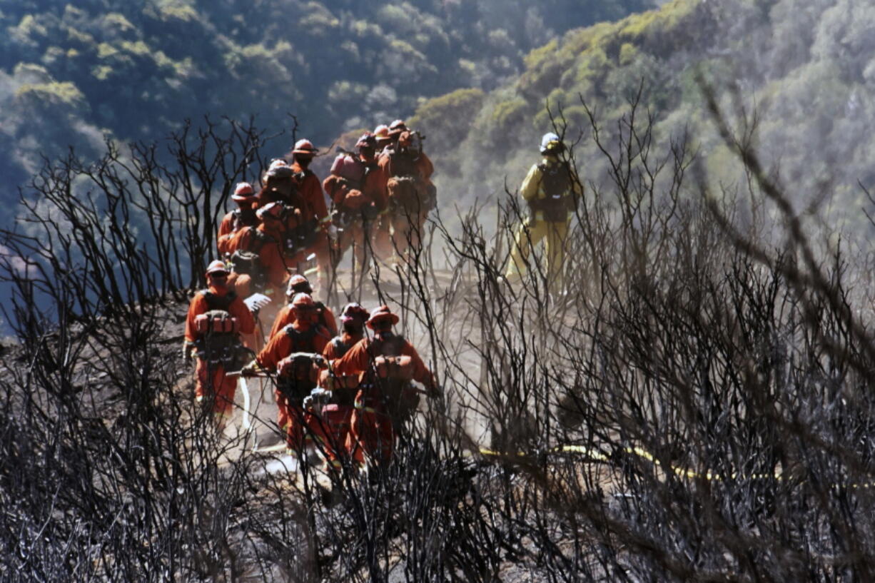 CAL FIRE Inmate Firefighting Hand Crew members hike through the charred landscape on their way to work east of Gibraltar Road above Montecito, Calif., Tuesday, Dec. 19, 2017. Officials estimate that the fire will grow to become the biggest in California history before full containment, expected by Jan. 7.