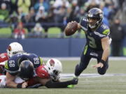 Seattle Seahawks quarterback Russell Wilson, right, is tripped by Arizona Cardinals outside linebacker Chandler Jones, second from right, in the second half of an NFL football game, Sunday, Dec. 31, 2017, in Seattle.