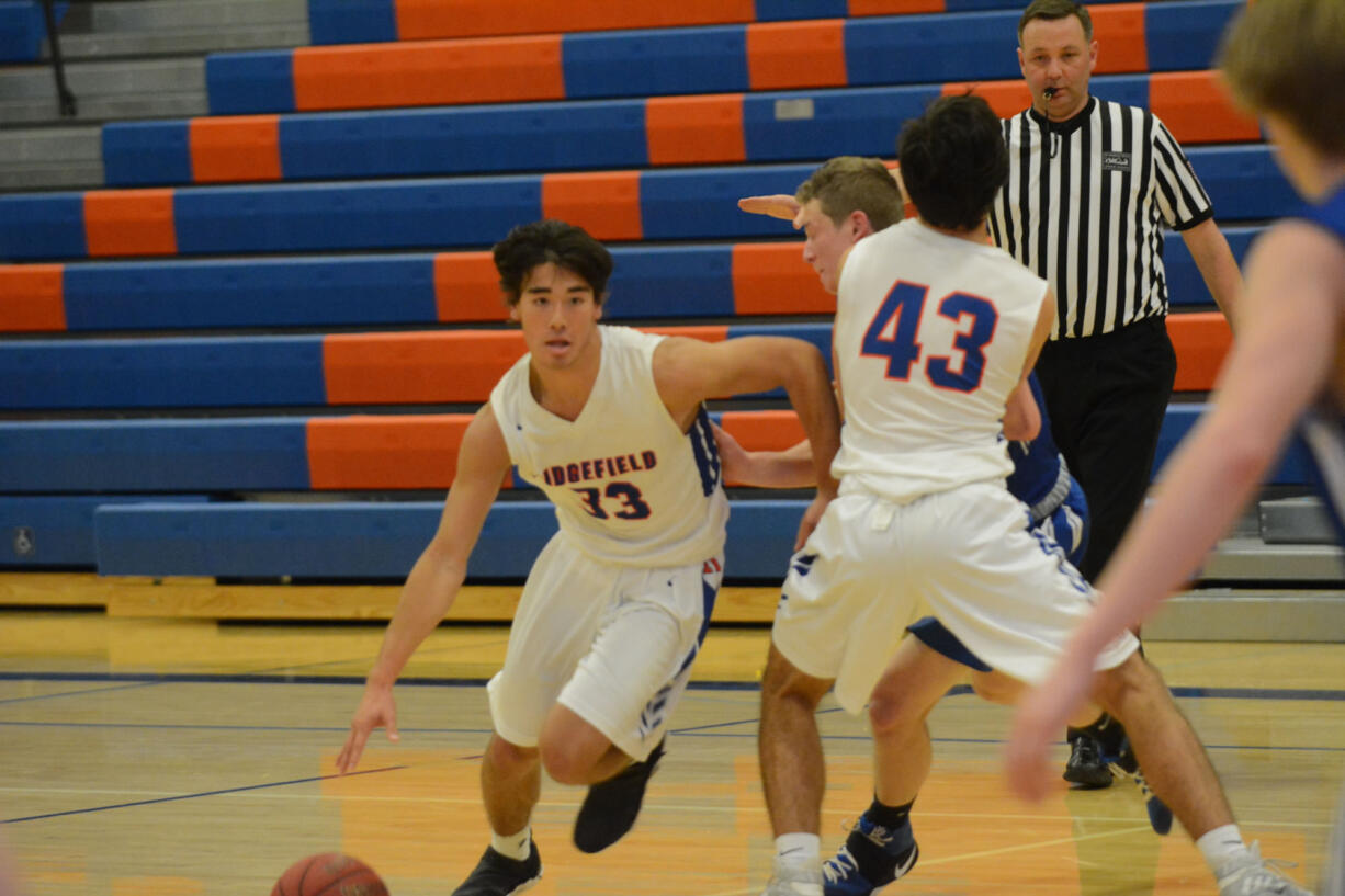 Kellen Bringhurst (left) goes around a hard pick from a teammates in the third quarter of Ridgefield's 56-55 win over La Center on Dec.