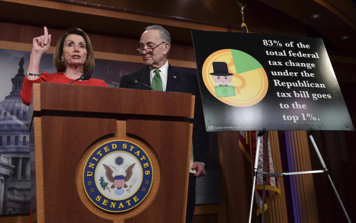 FILE - In this Dec. 20, 2017, file photo, House Minority Leader Nancy Pelosi of Calif., left, standing with Senate Minority Leader Sen. Chuck Schumer of N.Y., right, speaks at a news conference on Capitol Hill in Washington. Democratic candidates in the 2018 midterms plan to argue that the legislation favors the wealthy and breaks President Donald Trump and Republicans’ promises to the middle class.