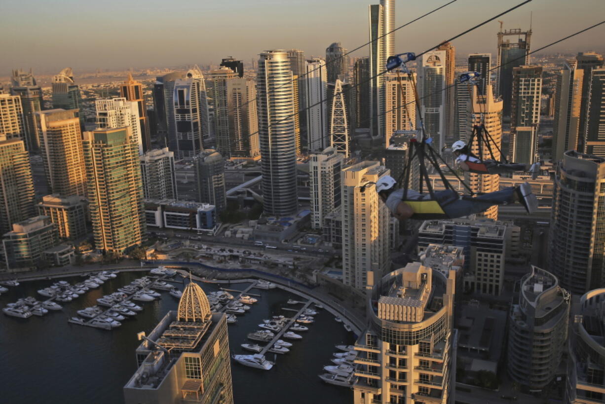 Two people ride the world's longest urban zip line with a speed of up to 80 kilometers per hour on a one kilometer run from 170 meter to ground level, at the Marina district of Dubai, United Arab Emirates, Tuesday, Dec. 5, 2017.