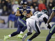 Seattle Seahawks quarterback Russell Wilson, left, scrambles as Philadelphia Eagles’ Corey Graham (24) moves in during the first half of an NFL football game, Sunday, Dec. 3, 2017, in Seattle.