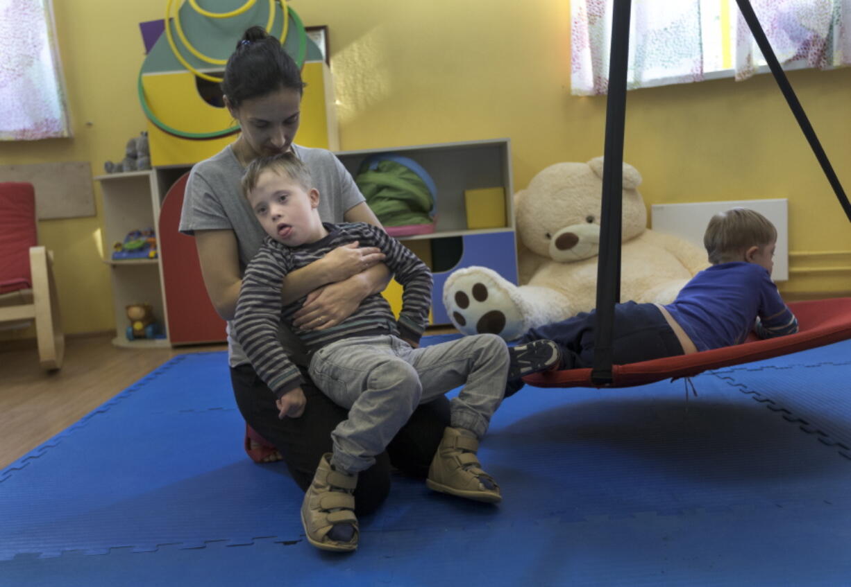 From left, tutor Vika, 11-year-old pupil, Anton, and 9-year-old Arkhip work in a room at the St. Sophia orphanage in Moscow on Sept. 12. Historically, Russia’s orphanage system has been tightly controlled by the government. Now, for the first time, an orphanage outside state control has been set up to care for children with severe disabilities: St. Sophia’s, run by the Russian Orthodox Church.