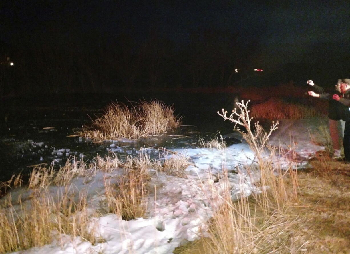 In this Monday, Dec. 25, 2017 photo provided by the Washington County Sheriffs Office, a search and rescue team work on the edge of a frozen pond in the town of New Harmony, north of St. George, Utah. A sheriff’s deputy in southern Utah punched through the frozen pond on Christmas Day to rescue drowning 8-year-old boy. Washington County sheriff’s Lt. David Crouse said the boy was chasing his dog Monday evening when another child saw him fall through the ice.