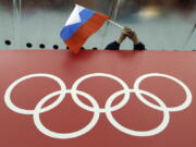 FILE - In this Feb. 18, 2014, file photo, a Russian skating fan holds the country's national flag over the Olympic rings before the start of the men's 10,000-meter speedskating race at Adler Arena Skating Center during the 2014 Winter Olympics in Sochi, Russia. Russia could be banned from competing at the Pyeongchang Olympics. The decision will come on Tuesday, Dec. 5, 2017 when the International Olympic Committee executive board meets in Lausanne, less than nine weeks before the games open on Feb. 9 in South Korea. (AP Photo/David J.