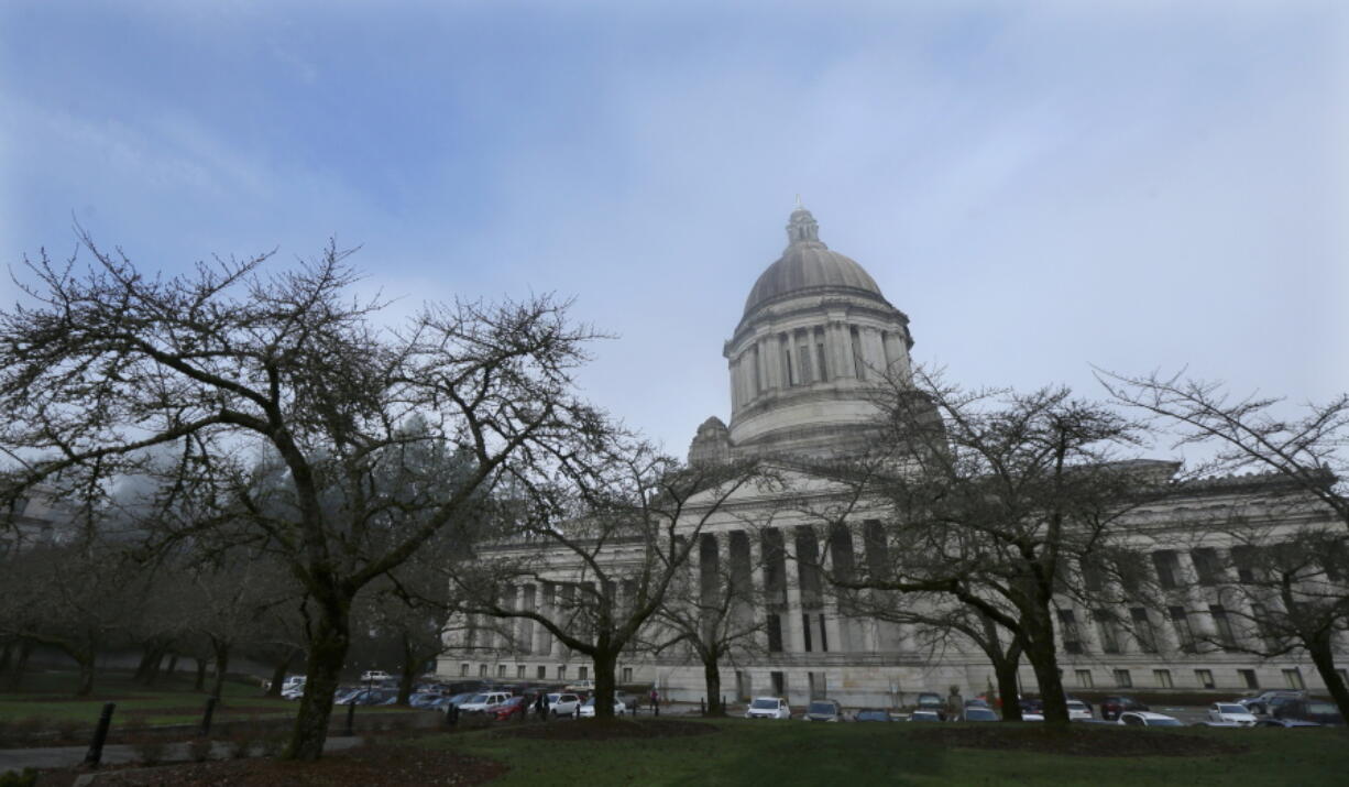 Bare trees and lifting fog frame the view of the Legislative Building at the Capitol in Olympia, Wash., Thursday, Dec. 14, 2017, the day Gov. Jay Inslee unveiled his supplemental budget proposal. Inslee proposed tapping the state’s reserves to meet a final timeline required for Washington state to comply with a state Supreme Court mandate on education funding, and he wants a new tax on carbon emissions from fossil fuels to ultimately backfill that withdrawal. (AP Photo/Ted S.