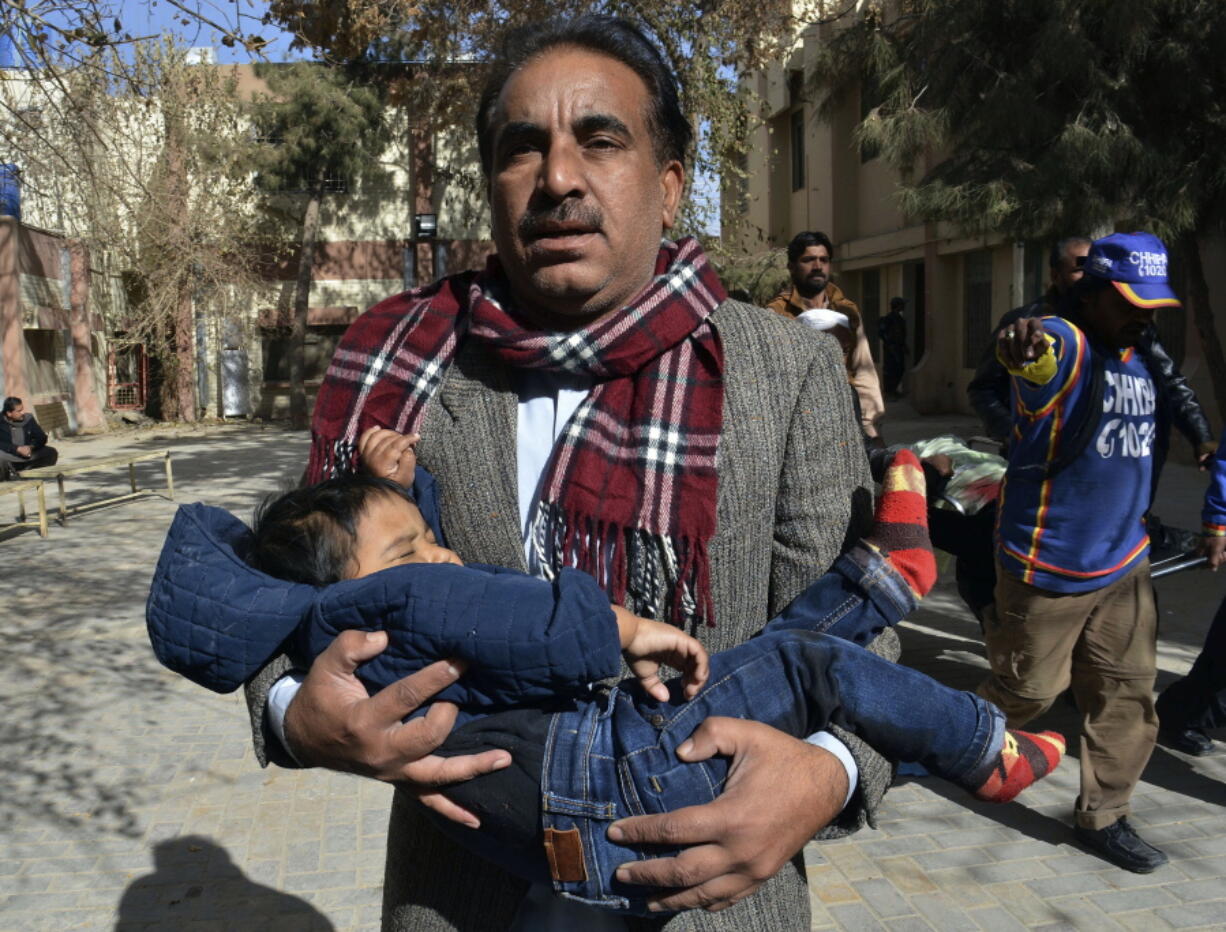 A volunteer rescues a child while others removing a body following the suicide attack on a church in Quetta, Pakistan, Sunday, Dec. 17, 2017. Two suicide bombers attacked the church when hundreds of worshippers were attending services ahead of Christmas.