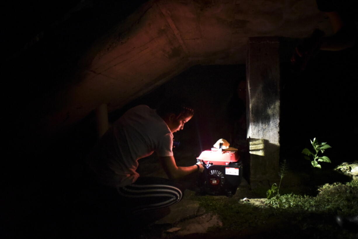 In this Dec. 21, 2017 photo, barrio Patron resident Karina Santiago Gonzalez works on a small power plant in Morovis, Puerto Rico. More than three months have passed since Hurricane Maria.