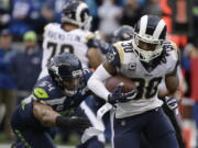 Los Angeles Rams running back Todd Gurley carries the ball as he gets ahead of Seattle Seahawks middle linebacker Bobby Wagner, left, Sunday in Seattle. Gurley had three touchdowns in the first half, while Wagner struggled with a hamstring injury that nearly prevented him from playing.