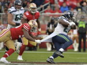 Seattle Seahawks running back Eddie Lacy, right, has his jersey pulled by San Francisco 49ers defensive end Ronald Blair during the first half of an NFL football game Sunday, Nov. 26, 2017, in Santa Clara, Calif.