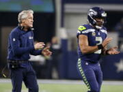 Seattle Seahawks head coach Pete Carroll and quarterback Russell Wilson walk onto the field in the second half of an NFL football game against the Dallas Cowboys on Sunday, Dec. 24, 2017, in Arlington, Texas.