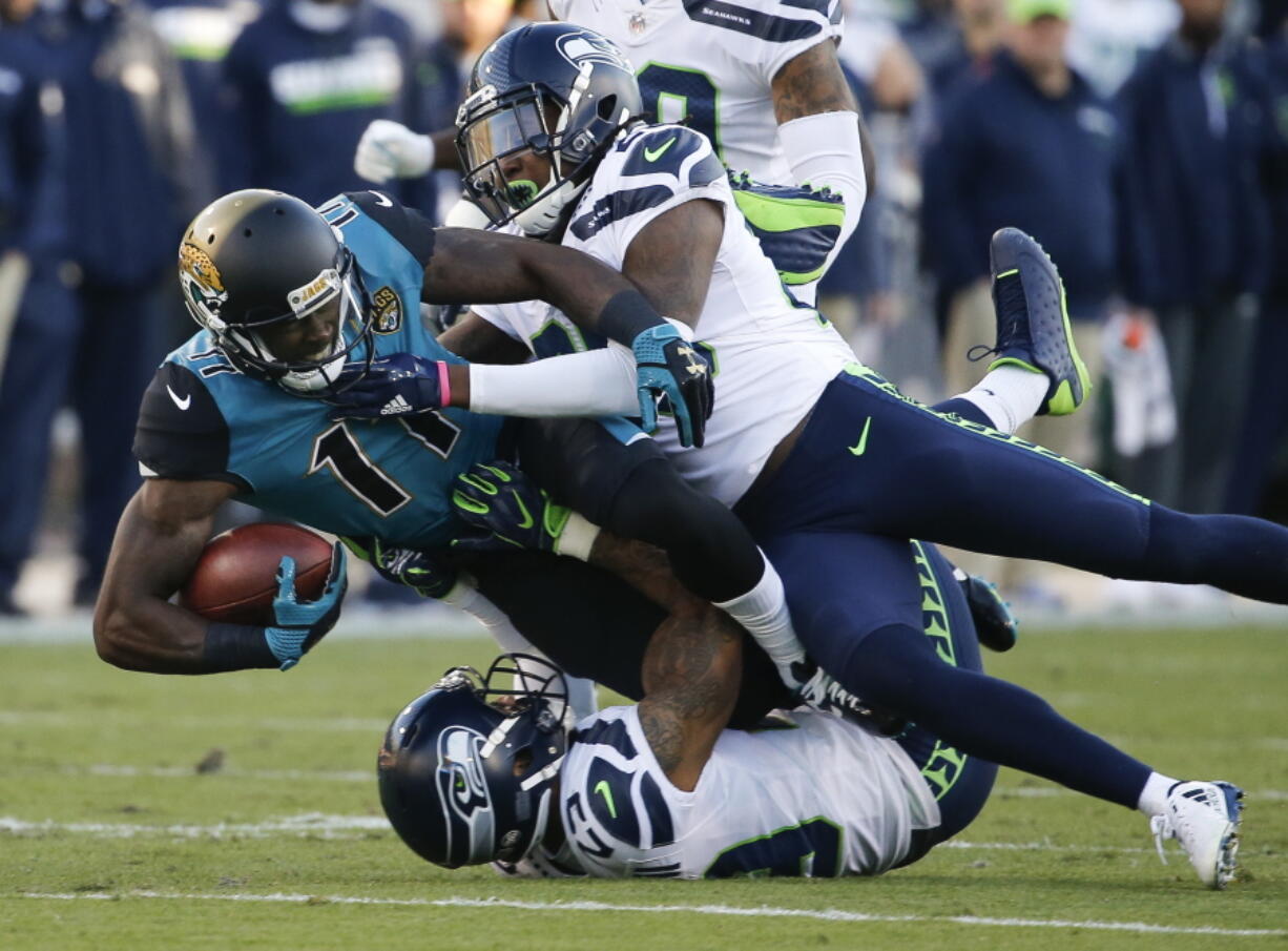 Jacksonville Jaguars wide receiver Marqise Lee (11) is tackled by Seattle Seahawks cornerback Shaquill Griffin, top right, and safety Earl Thomas, bottom, after a reception during the first half of an NFL football game, Sunday, Dec. 10, 2017, in Jacksonville, Fla. (AP Photo/Stephen B.