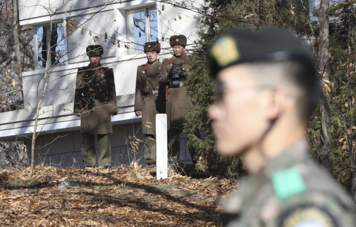 FILE - In this Nov. 27, 2017, file photo, North Korean soldiers look at the South side as a South Korean stands guard near the spot where a North Korean soldier crossed the border on Nov. 13 at the Panmunjom, in the Demilitarized Zone, South Korea. South Korea says on Thursday, Dec. 21, 2017, it has fired 20 rounds of warning shots as North Korean soldiers approached a military demarcation line at the border after their comrade defected to South Korea.