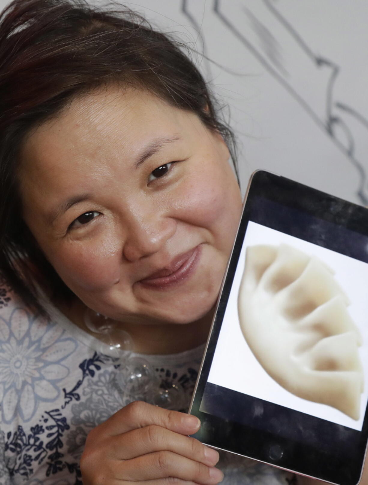 Jennifer 8. Lee holds an image of a dumpling emoji Wednesday at Dumpling Time restaurant in San Francisco. Thanks largely to Lee’s efforts, the dumpling emoji was added to the Unicode Standard this year after almost two years of research, meetings, and a written proposal.