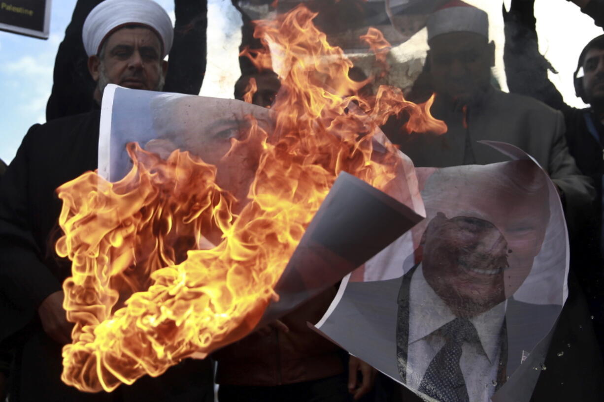 Palestinians burn posters of Israeli Prime Minister Benjamin Netanyahu and U.S. President Donald Trump on Thursday during a protest against the U.S. decision to name Jerusalem as Israel’s capital, in Gaza City.