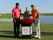 Rickie Fowler, right, poses with Tiger Woods and the trophy after Fowler won the Hero World Challenge golf tournament at Albany Golf Club in Nassau, Bahamas, Sunday, Dec. 3, 2017.