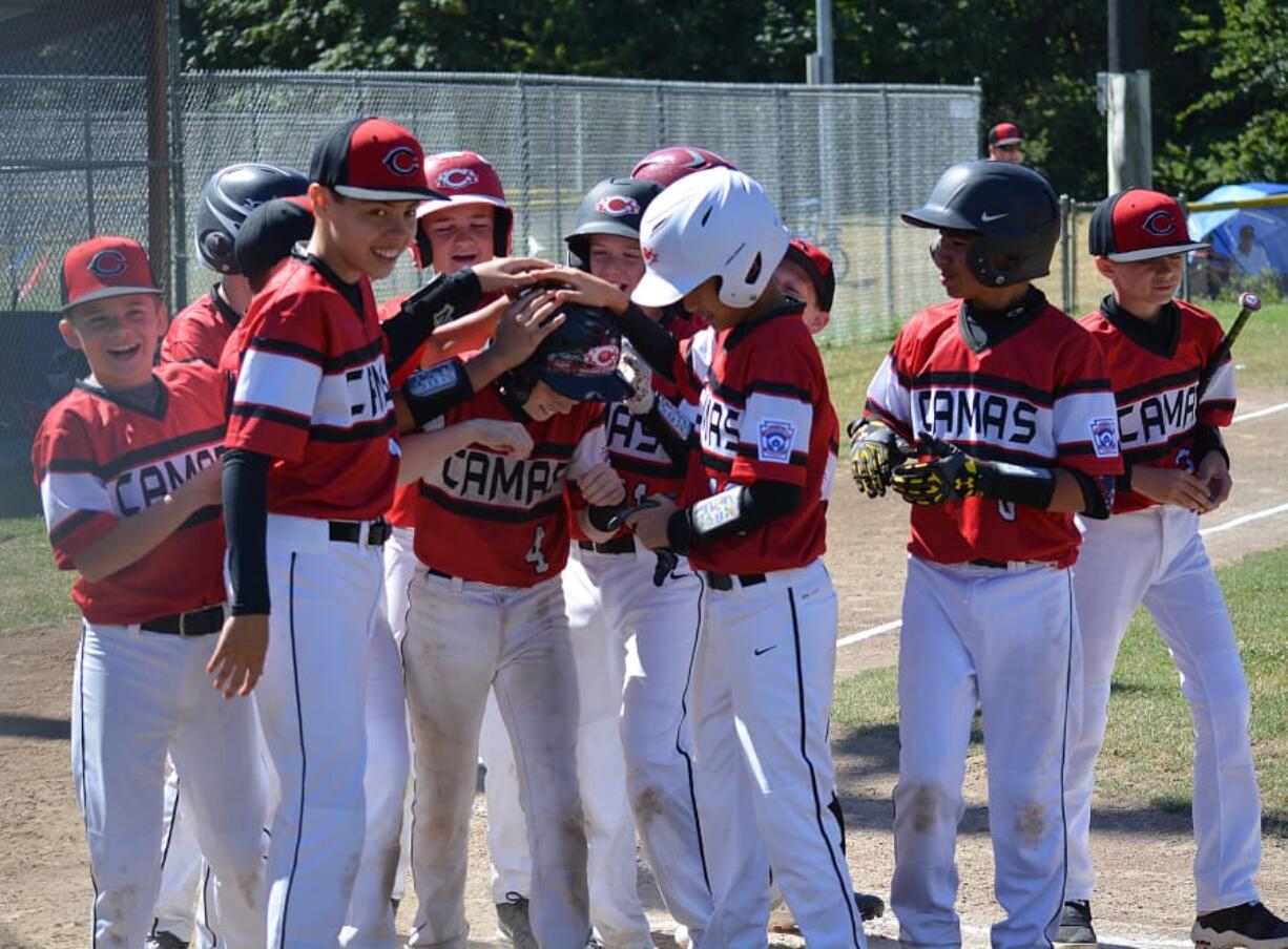 Jackson Knuth gets patted down by his teammates at home plate after hitting a home run for the Camas Little League Major all-star baseball team last summer.