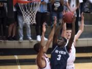 Skyview’s Samaad Hector (3) tries to leap past Camas’ Gabriel Mukobi (15) and Carson Bonine (10) for a layup. Hector scored a game-high 17 points in leading the Storm to a 53-51 win over the Papermakers.