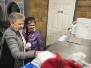 Volunteer Bert Day of Vancouver helps Deana Lentz, homeless in Vancouver, start up a loaded washer during the free laundry night at Laundry Love on Thursday evening, Jan. 4, 2018. The laundromat opened this winter after undergoing repairs from an accident in May.