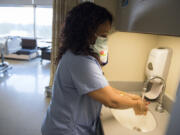 Certified nursing assistant Meron Mesfin washes her hands before entering the rooms of influenza patients on Tuesday afternoon at PeaceHealth Southwest Medical Center in Vancouver. The hospital has additional precautionary measures in place — such as masks and extra handwashing — to prevent the spread of influenza.