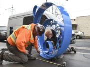 Jamason Lindeman of Robertson and Olson Construction, left, and metal artist Dave Frei of Cobalt Designworks, consider the final placement of “Bubbles,” a metal sculpture that’ll contribute some deep blue to the Washington Street sidewalk outside the new Uptown Apartments.