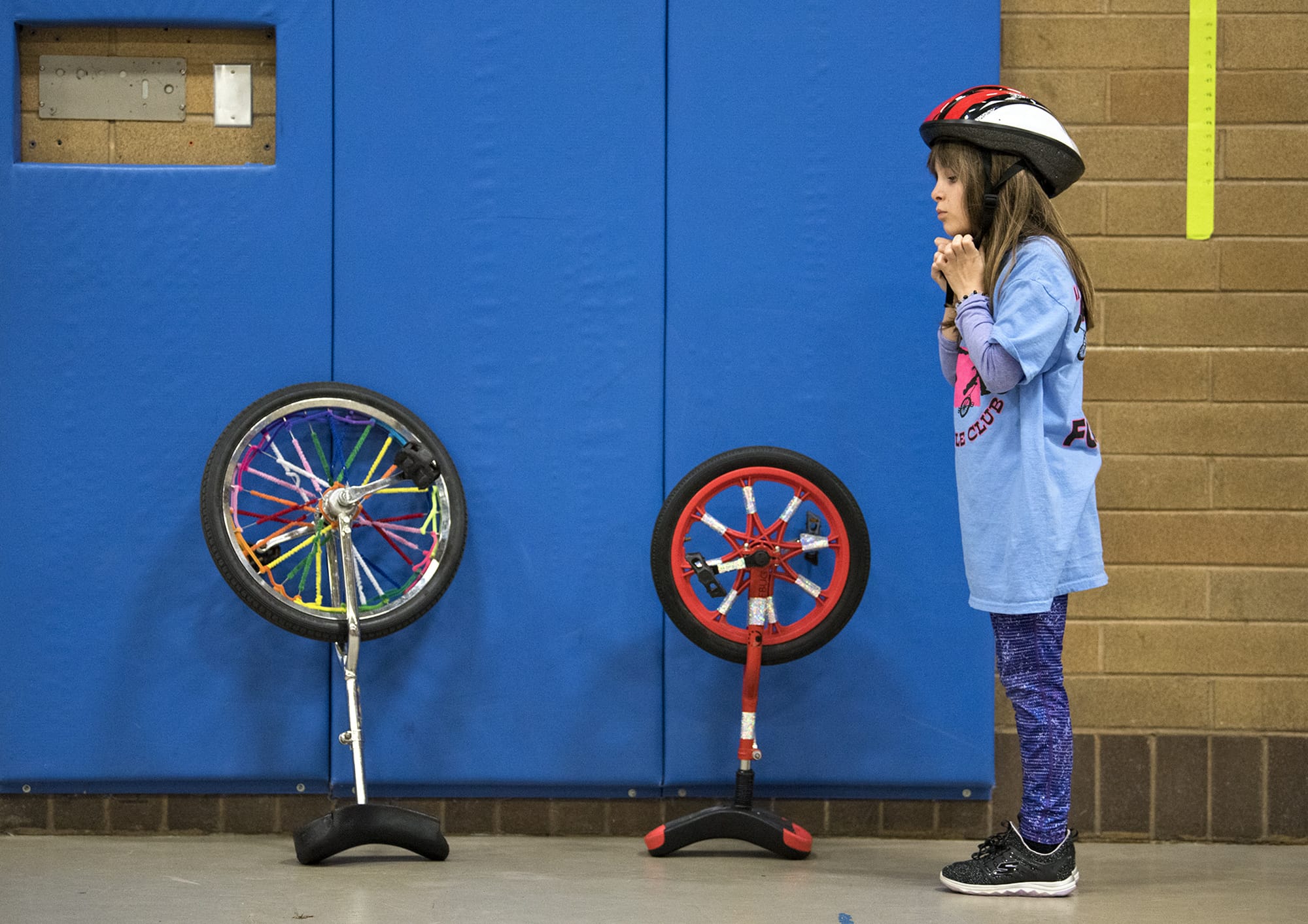 SHelmets? Of course they’re mandatory, coach Paul White said. Here, 10-year-old Maddie Steinman adjusts her helmet before joining the action during a Pleasant Valley Unicycle Team practice session.