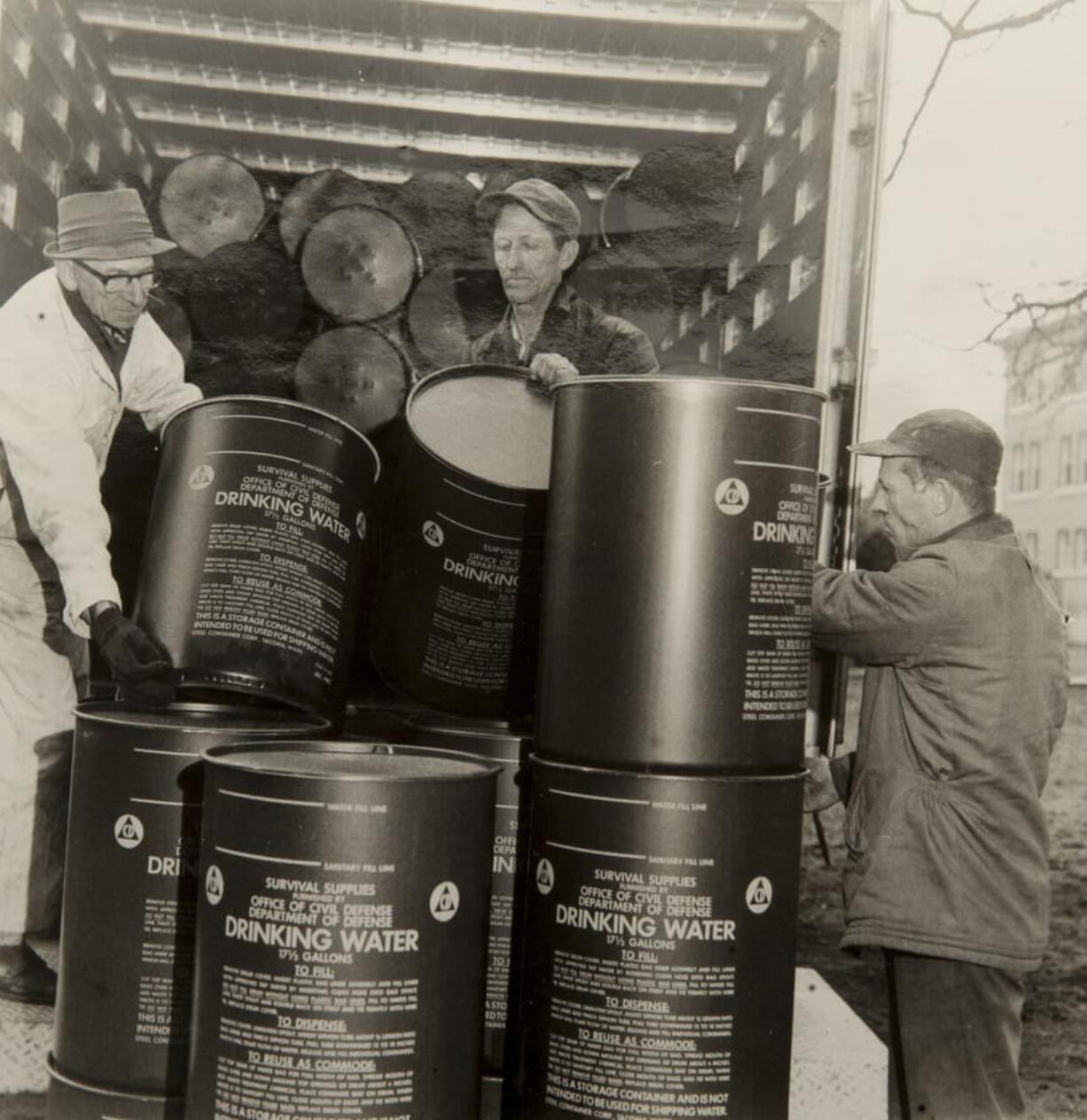 Local men collect survival supplies, such as these barrels of drinking water, in 1963.