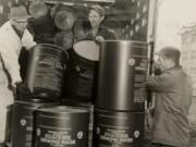 Local men collect survival supplies, such as these barrels of drinking water, in 1963.