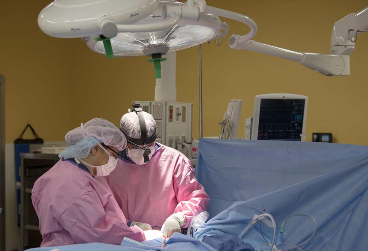 Dr. Toni Storm-Dickerson, left, and Dr. Allen Gabriel place the BioZorb implant into the breast of Dr. Anne Peled, a breast cancer surgeon from California, during lumpectomy and oncoplastic surgery Tuesday at PeaceHealth Southwest Medical Center. The oncoplastic surgery uses breast tissue to fill the void left by the removed tumor. The implant serves as a marker of the cancer location for future radiation treatment.