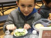 Five Corners: Sunset Elementary School student Cristian Trigueros tastes a Cool Kale Caesar Salad during lunch. Kale is the special ingredient this month at Evergreen Public Schools elementary schools through the Washington State University Extension’s Supplemental Nutrition Assistance Program Education’s Harvest of the Month program.