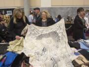 Jan Aamodt, center, looks at a vintage table cloth Saturday at the Clark County Antique & Collectible Show at the Clark Country Event Center at the Fairgrounds. The show featured dishes, posters, knick knacks and textiles, among other items.