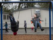 La Center Elementary School fifth-graders Carter Sherry, 10, left, and Jackson Simmonds, 11, catch a ride on the swings during recess near two of the nine portable classrooms at K-8 campus in 2018.