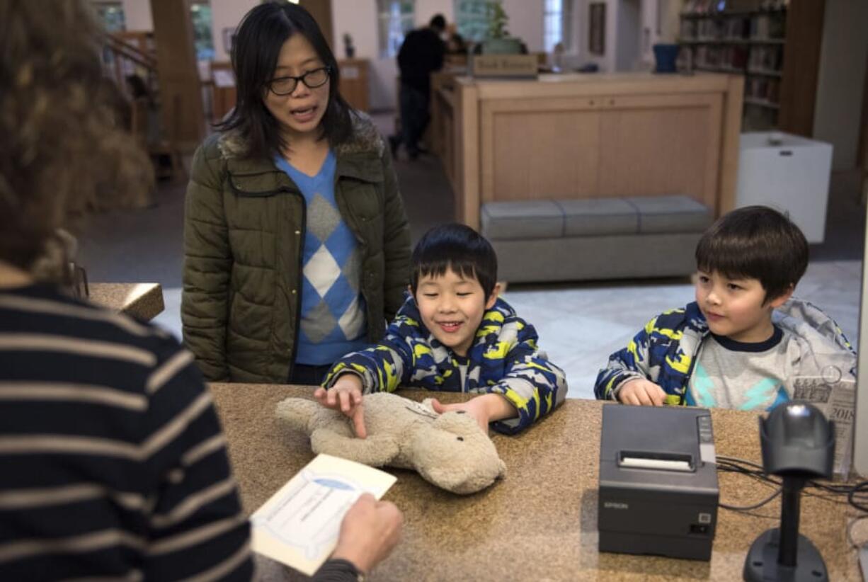 Boosakorn Co stands with her twin boys Lucas, center, and Bryson, right, both 5, as they pick up their stuffed animals from a sleepover at the Camas Public Library. Kids were invited to a special story time at the library Wednesday, where they left their stuffed animals at the library overnight and picked them up on Thursday, when they learned about their stuffed animals adventures during the sleepover.