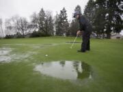 Jim Mewhirter of Vancouver attempts to putt around puddles on the first hole during a rainy golf game at Fairway Village on Thursday morning.