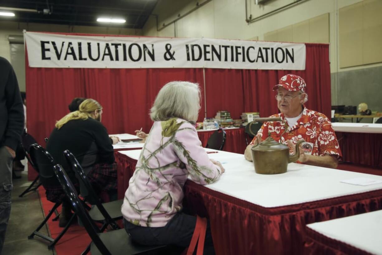 Randy Coe, right, of the International Society of Appraisers, discusses a vintage copper kettle at a recent Clark County Antique & Collectible show.