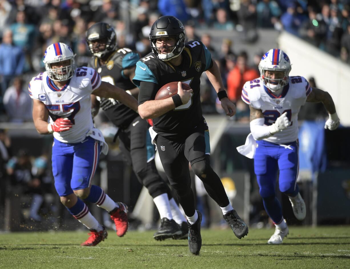 Jacksonville Jaguars quarterback Blake Bortles (5) rushes for yardage past Buffalo Bills outside linebacker Lorenzo Alexander (57) and free safety Jordan Poyer (21) in the first half of an NFL wild-card playoff football game, Sunday, Jan. 7, 2018, in Jacksonville, Fla. (AP Photo/Phelan M.