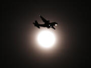 An airplane passes the full moon on its final approach before landing in Seoul, South Korea, Wednesday, Jan. 31, 2018. The moon is putting on a rare cosmic show. It's the first time in 35 years a blue moon has synced up with a supermoon and a total lunar eclipse.