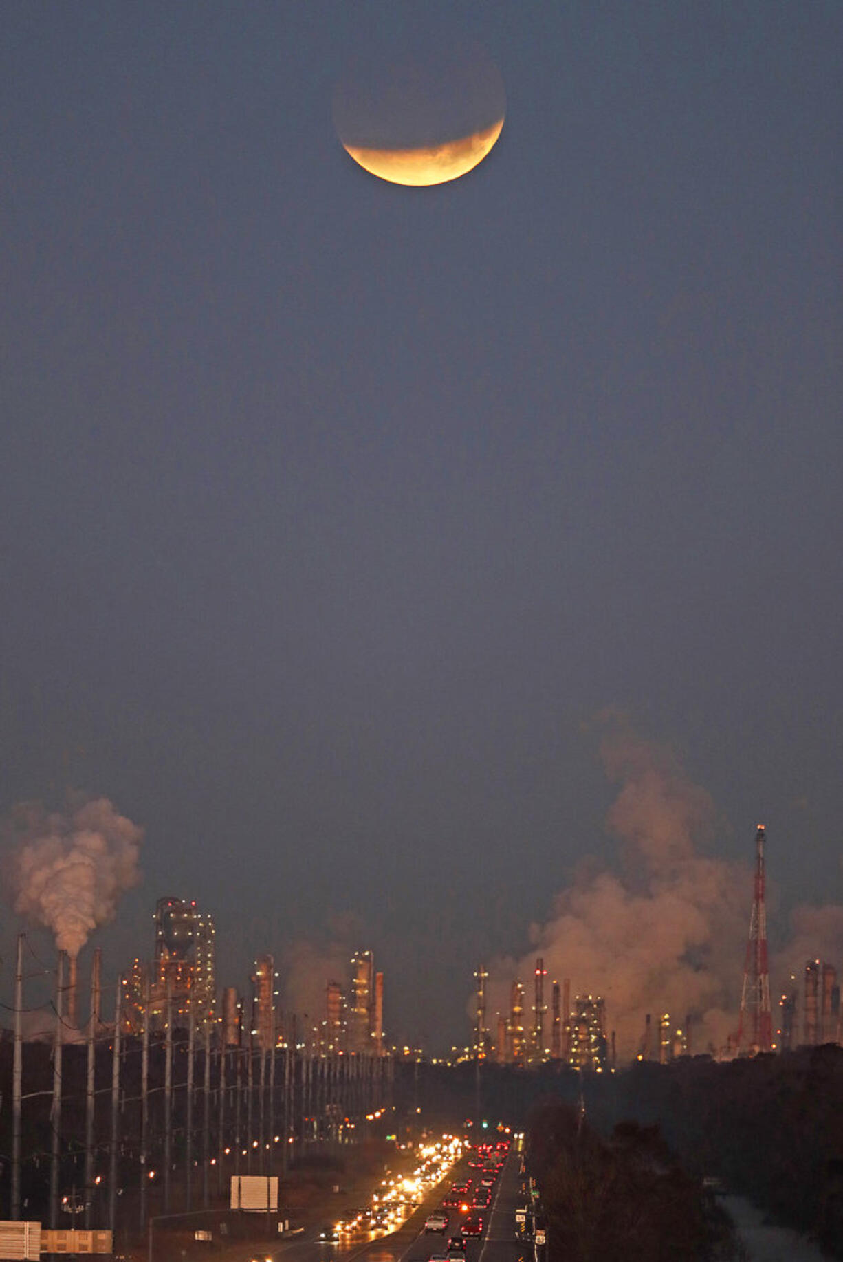 A supermoon, undergoes a partial eclipse as it sets beyond gas refineries, at sunrise in St. Charles Parish, La., Wednesday, Jan. 31, 2018.