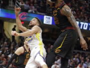 Cleveland Cavaliers’ LeBron James blocks a shot by Golden State Warriors’ Stephen Curry, left, in the second half of an NBA basketball game, Monday, Jan. 15, 2018, in Cleveland.