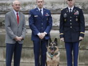 John Wren, left, with Military dog Ayron and his handler Staff Sergeant Jeremy Mayerhoffer, centre, and US Lieutenant Colonel Alan Throop, right, during a ceremony to posthumously award the PDSA Dickin Medal, , to Chips, in London, Monday.