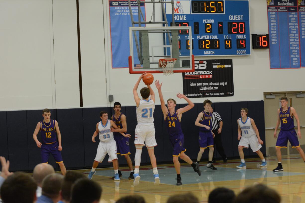 Mark Morris boys basketball player Garrett Berger (21) shoots a contested jump shot over Columbia River's Jack Armstrong (24) during the Monarchs' 45-42 win over River on Thursday, Jan.