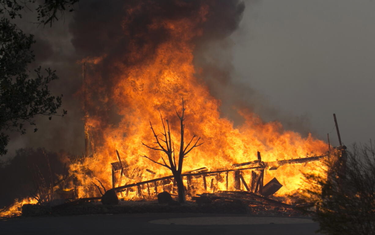 FILE - In this Monday Oct. 9, 2017 file photo flames from a wildfire consume a home, near Napa, Calif. Insurance claims for last year’s deadly California wildfires have reached $11.8 billion, Insurance Commissioner Dave Jones said Wednesday, Jan. 31, 2018.