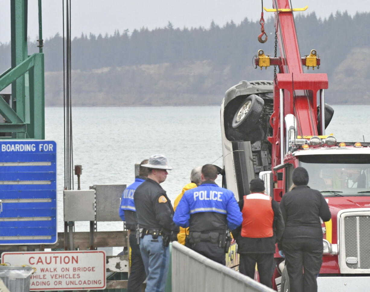 A tow truck lifts a white Jeep Cherokee vehicle out of the water at the Washington state ferry terminal Thursday in Anacortes. Authorities say a 30-year-old woman from Everett died after she drove her Jeep Cherokee through a barrier and off a dock.