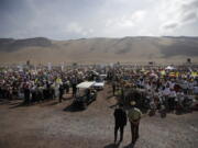 Security looks on as Pope Francis rides on a pope-mobile past the crowd as he arrives to celebrate Mass on Lobito Beach in Iquique, Chile, on Thursday. Pope Francis urged the people to continue to be welcoming toward migrants in this Chilean coastal city which has experienced a boom of immigrants from several countries.