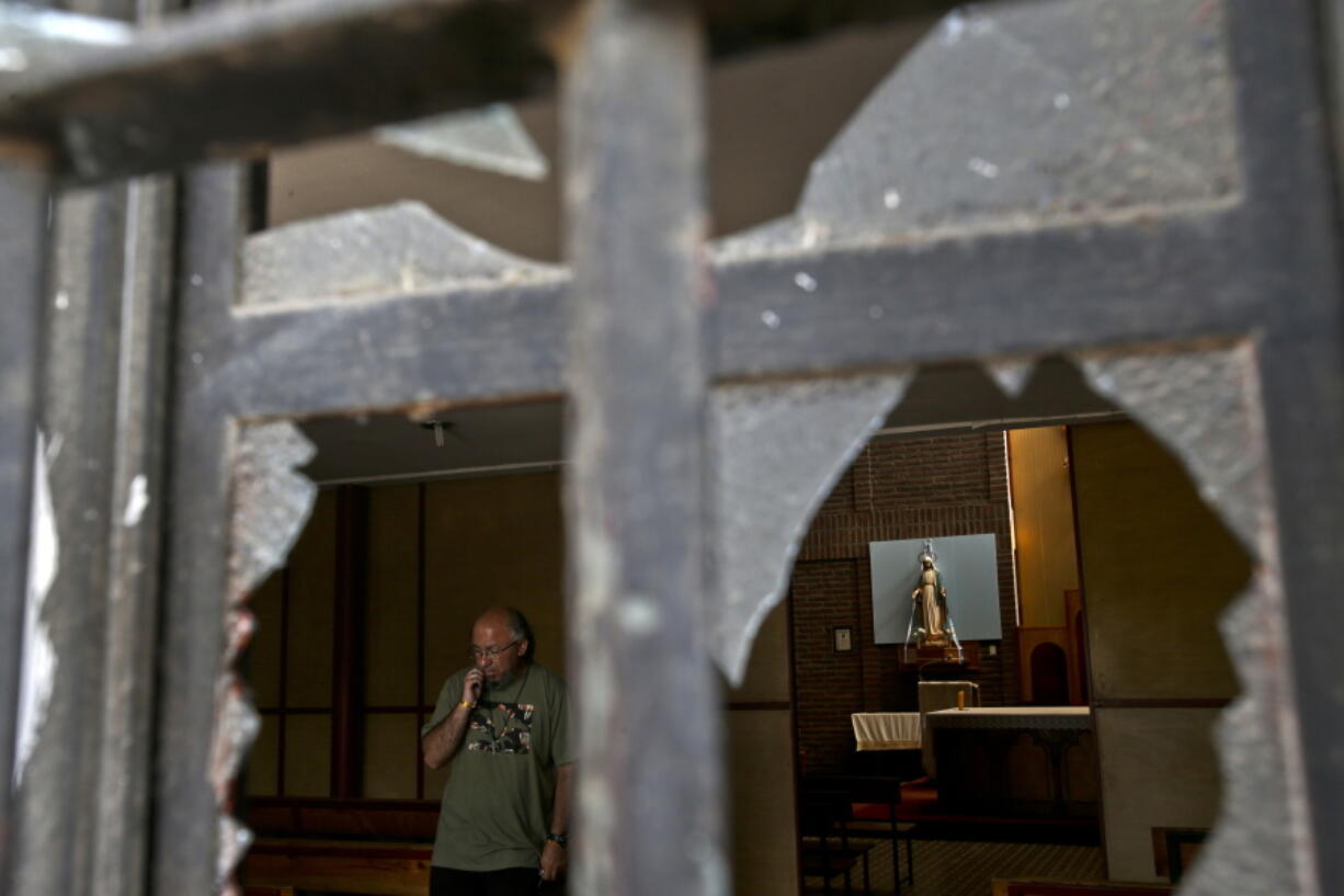 A church employee surveys the damage caused by an overnight fire bomb attack at the Emmanuel Catholic Church, in Santiago, Chile, on Friday. Three churches were attacked with fire bombs in Santiago overnight, dropping leaflets at the scene against the upcoming visit of Pope Francis, and calling for a “free” Mapuche nation. Nobody was injured or arrested.