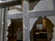 A church employee surveys the damage caused by an overnight fire bomb attack at the Emmanuel Catholic Church, in Santiago, Chile, on Friday. Three churches were attacked with fire bombs in Santiago overnight, dropping leaflets at the scene against the upcoming visit of Pope Francis, and calling for a “free” Mapuche nation. Nobody was injured or arrested.