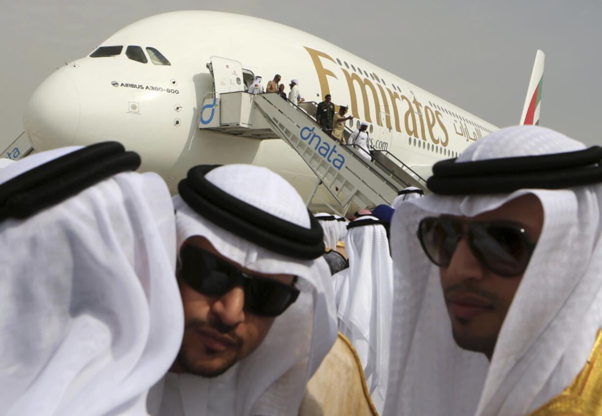 FILE - In this Nov. 17, 2013 file photo, Emirati officials greet each other in front of an Emirates Airbus A380 on display during the opening day of the Dubai Airshow in Dubai, United Arab Emirates. Emirates airline said in a statement Thursday, Jan. 18, 2018, that they are purchasing 20 A380 aircraft with the option for 16 more in a deal worth $16 billion, throwing a lifeline to the European-made double-decker jumbo jets.