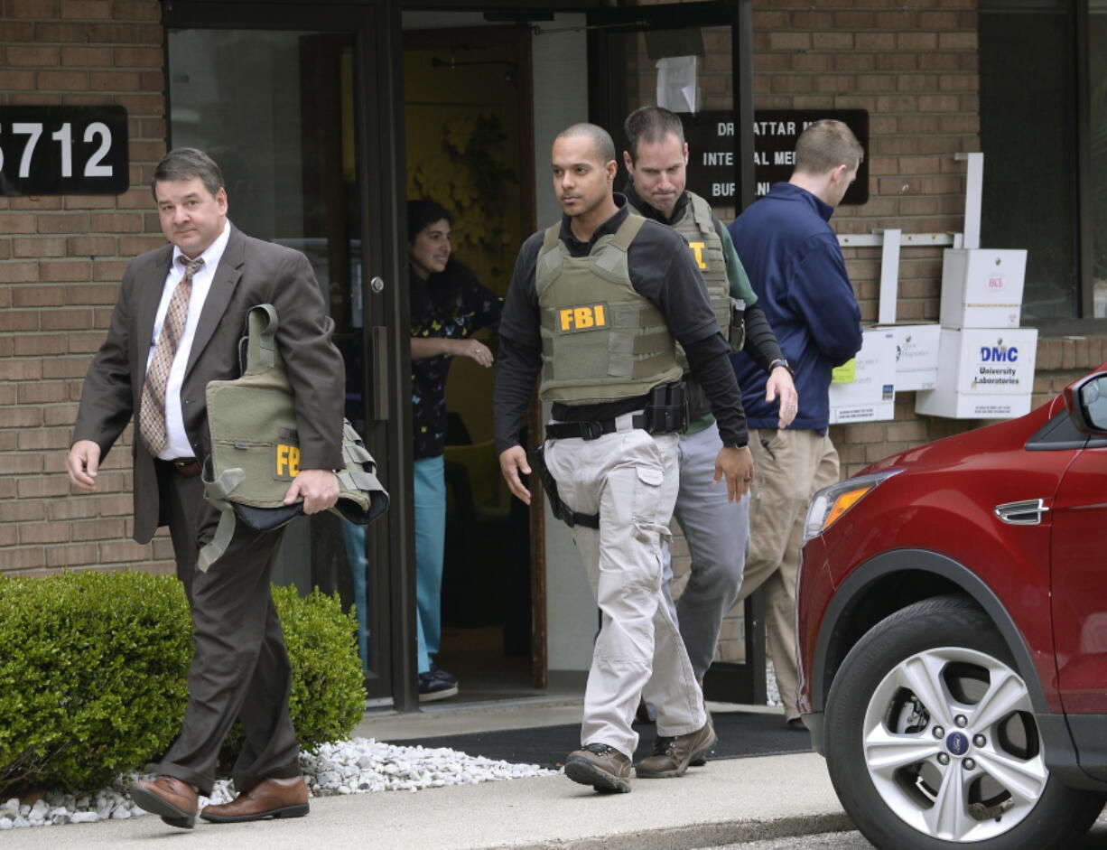 FILE - In this April 21, 2017 file photo, FBI agents leave the office of Dr. Fakhruddin Attar at the Burhani Clinic in Livonia, Mich., after completing a search for documents. A federal judge in Detroit has dismissed one charge against Attar and Dr. Jumana Nagarwala in connection with a female genital mutilation case. U.S. District Judge Bernard Friedman ruled Sunday, Jan. 14, 2018, that the doctors didn’t commit conspiracy to transport a minor with intent to engage in criminal sexual activity. (Clarence Tabb Jr.