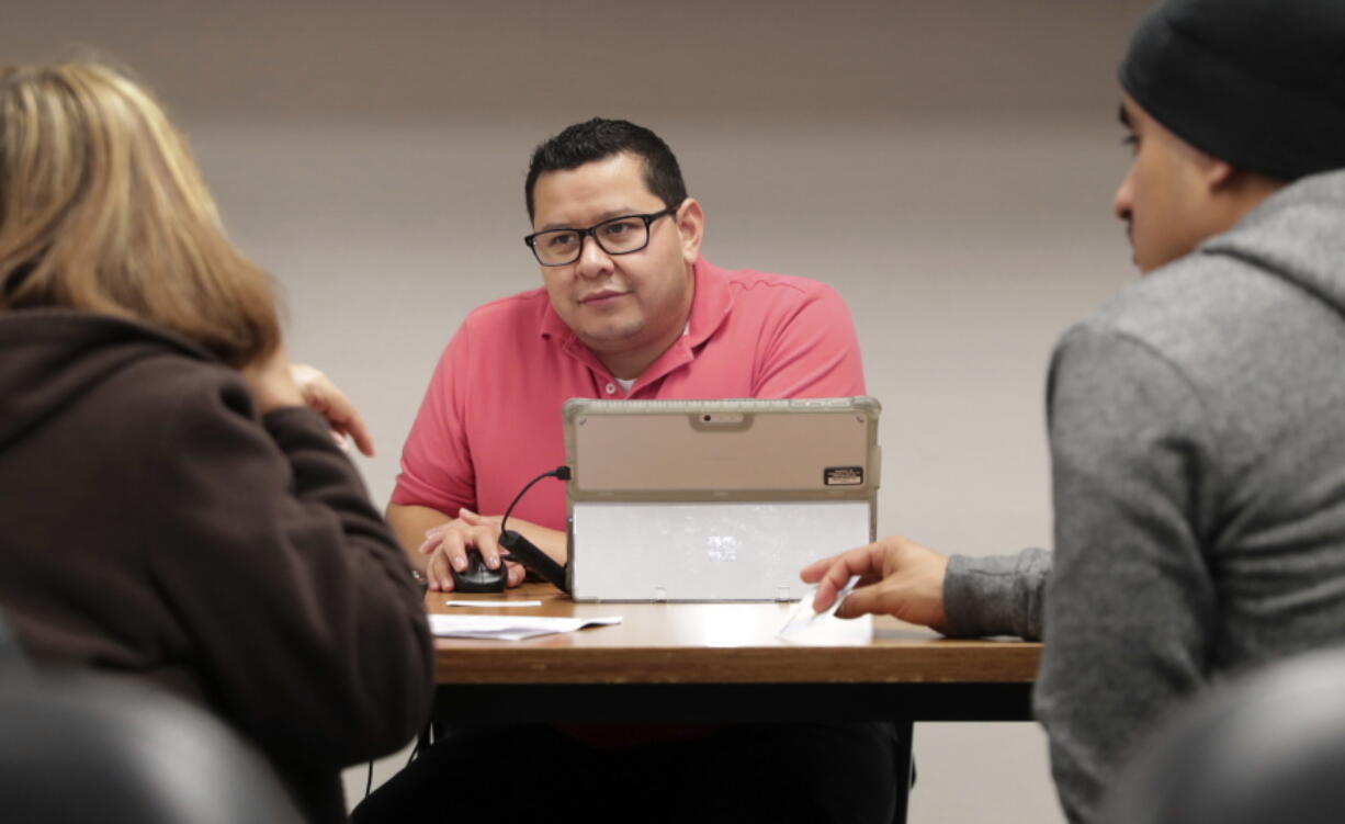 Community Council health care navigator Fidel Castro Hernandez, center, listens to legal U.S. resident Maria Ana Pina, left, as she signs up for the Affordable Care Act with her son Roberto Pina at the Community Council offices in Dallas.