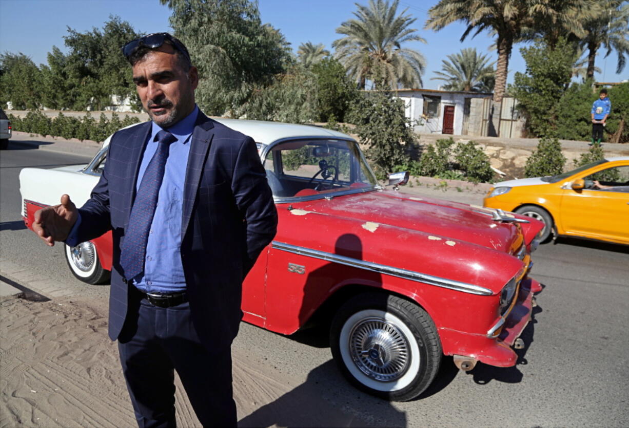 In this Friday, Jan. 12, 2018 photo, Nashwan Shakir Mahmoud stands with his his red and white 1955 Chevrolet coupe that survived three years of war and upheaval, in Baghdad, Iraq. The promise of better days after Iraq’s victory against the Islamic State group is rekindling interest in vintage cars.